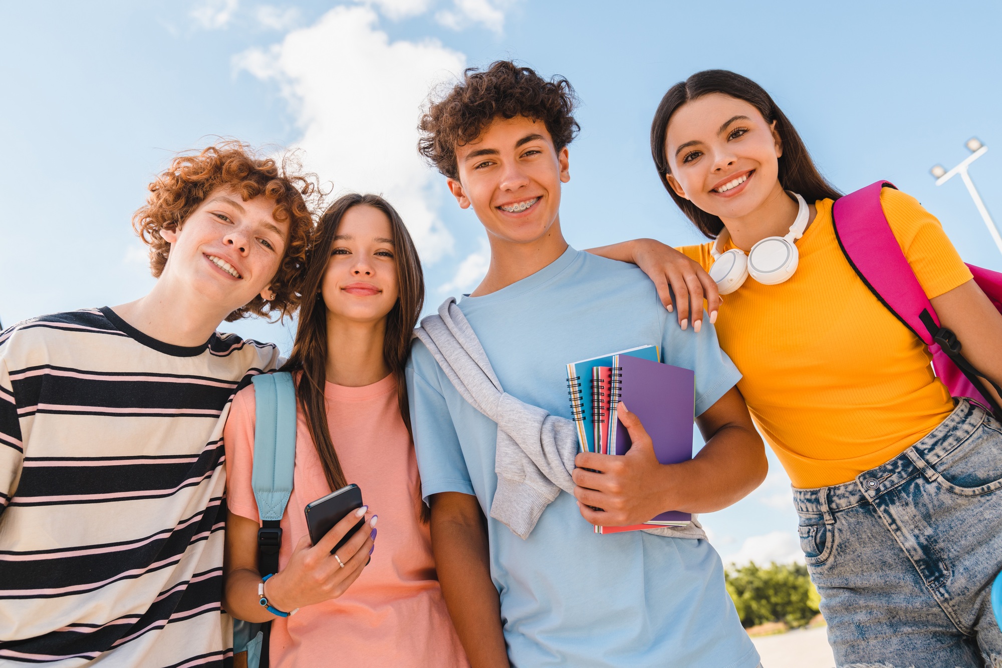 Close up photo of teenagers high school pupils college students hanging out in skate green park