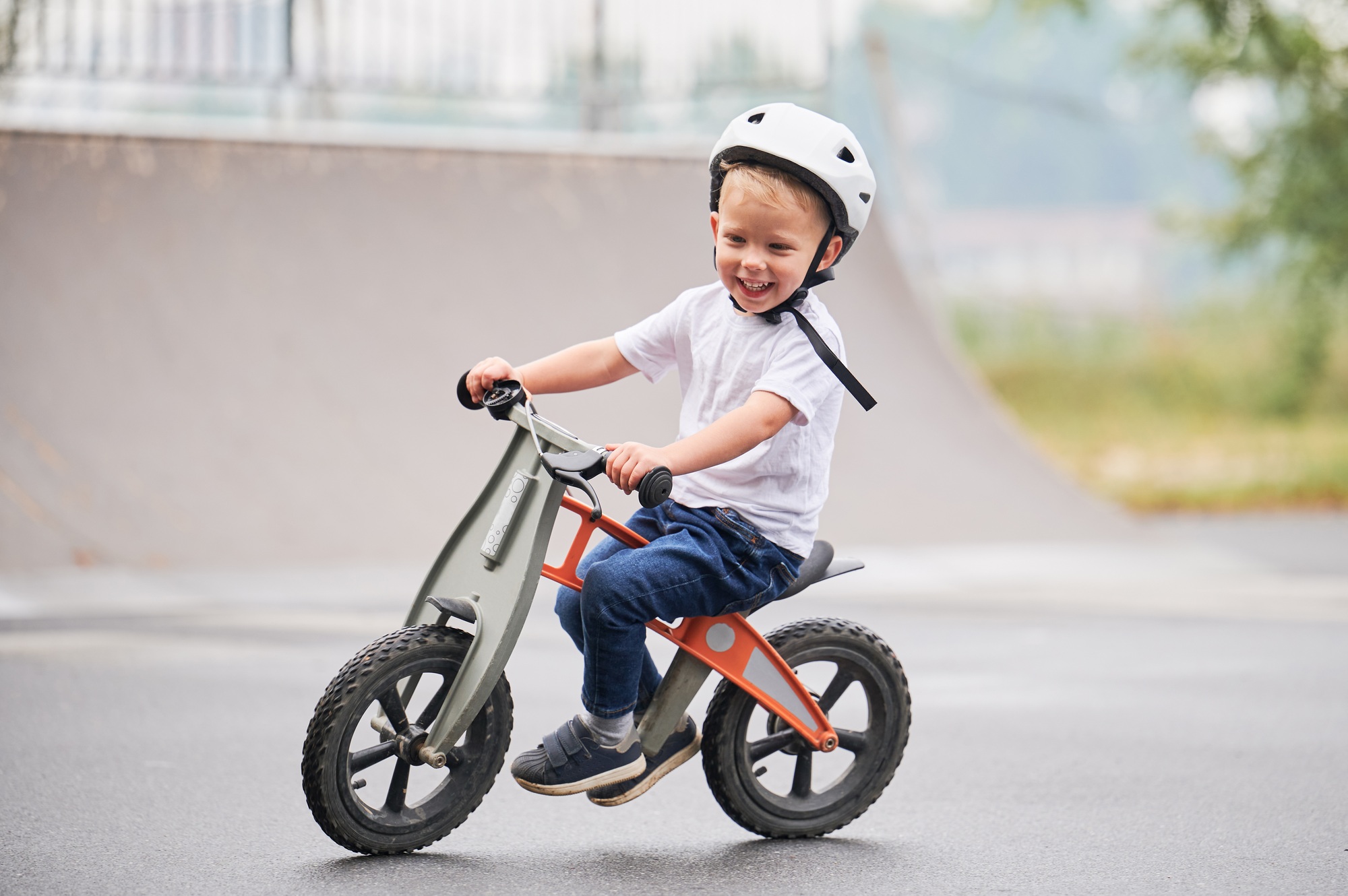 Toddler kid learning to ride on run bicycle at skate park.