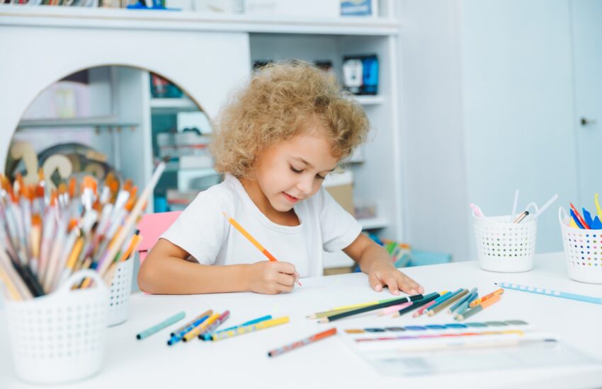 Cute little blonde preschooler girl draws at home