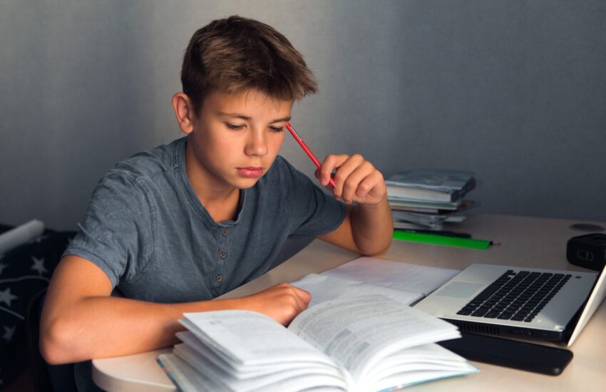 teenager boy doing homework with laptop