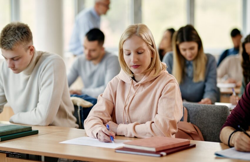 Young woman writing exam in lecture hall at the university.